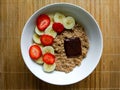 Breakfast bowl with strawberries and banana, with cereals and an ounce of dark chocolate Royalty Free Stock Photo