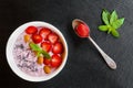 Breakfast bowl with yogurt, granola or muesli or oat flakes, fresh strawberry and mint. Black stone background, vintage spoon Royalty Free Stock Photo