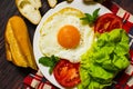 Breakfast with bread, fried eggs, milk and vegetables and fried tomato pieces on wood background. Royalty Free Stock Photo