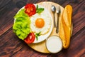 Breakfast with bread, fried eggs, milk and vegetables and fried tomato pieces on wood background. Royalty Free Stock Photo