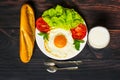 Breakfast with bread, fried eggs, milk and vegetables and fried tomato pieces on wood background. Royalty Free Stock Photo