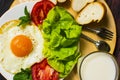 Breakfast with bread, fried eggs, milk and vegetables and fried tomato pieces on wood background. Royalty Free Stock Photo
