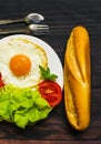 Breakfast with bread, fried eggs and vegetables and fried tomato pieces on wood background. Royalty Free Stock Photo