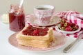 Breakfast of bread toasts with butter and strawberry-rhubarb jam, served with tea. Rustic style. Royalty Free Stock Photo