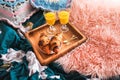 Breakfast brought to bed on a wooden tray. Orange juice in glasses and sweet croissants.