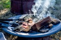 Breakfast camp cooking. grilling crispy bacon on a cast iron plate over the camp fire