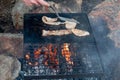 Breakfast camp cooking. Grilling crispy bacon on a cast iron plate over the camp fire Royalty Free Stock Photo
