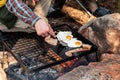 Breakfast camp cooking. Grilling crispy bacon and eggs on a cast iron plate over the camp fire Royalty Free Stock Photo