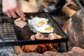 Breakfast camp cooking. Grilling crispy bacon and eggs on a cast iron plate over the camp fire Royalty Free Stock Photo