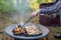 Breakfast camp cooking. Man grilling crispy bacon over the camp fire