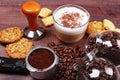 Breakfast with cappuccino, crackers, holder with ground coffee, tamper and coffee beans on wooden table Royalty Free Stock Photo