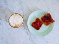 Breakfast with cappuccino and toasted bread with jam served on a marble table Royalty Free Stock Photo