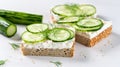 Breakfast, cereal bread sandwiches, cream cheese, sliced cucumber, with micro greenery on a light table