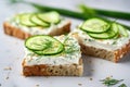 Breakfast, cereal bread sandwiches, cream cheese, sliced cucumber, with micro greenery on a light table