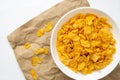 Breakfast cereal concept, Cornflakes in bowl and cornflakes fragments falling on brown paper