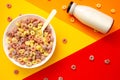 Breakfast cereal concept, Fruit ring cereals in bowl and milk in bottle on colorful background Royalty Free Stock Photo