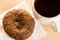 Breakfast of coffee and chocolate glazed donut on table