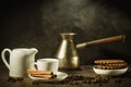 Breakfast with coffee and cookies/coffee cup with cinnamon, old pot, creamer and chocolate cookies on a wooden table. Against Royalty Free Stock Photo