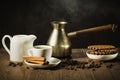 breakfast with coffee and cookies/coffee cup with cinnamon, old pot, creamer and chocolate cookies on a wooden table. selective Royalty Free Stock Photo