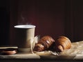 Breakfast with coffee cup and two croissants on a wooden table in sunlight. Royalty Free Stock Photo