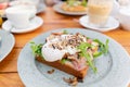Breakfast and coffee in the summer cafe. Sandwich on a bun brioche with bacon, mushrooms, arugula and poached egg