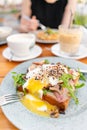 Breakfast and coffee in the summer cafe. Sandwich on a bun brioche with bacon, mushrooms, arugula and poached egg