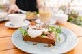 Breakfast and coffee in the summer cafe. Sandwich on a bun brioche with bacon, mushrooms, arugula and poached egg