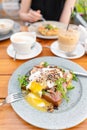 Breakfast and coffee in the summer cafe. Sandwich on a bun brioche with bacon, mushrooms, arugula and poached egg