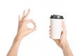 Breakfast and coffee theme: man's hand holding white empty paper coffee cup with a brown plastic cap isolated on a white backgroun Royalty Free Stock Photo