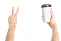 Breakfast and coffee theme: man's hand holding white empty paper coffee cup with a brown plastic cap isolated on a white backgroun Royalty Free Stock Photo