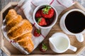 Breakfast concept. Cup of coffee, freshly baked croissants and fresh strawberry on wooden tray Royalty Free Stock Photo