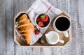 Breakfast concept. Cup of coffee, freshly baked croissants and fresh strawberry on wooden tray Royalty Free Stock Photo