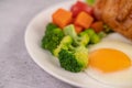 Breakfast consisting of bread, fried eggs, broccoli, carrots, tomatoes and lettuce on a white plate Royalty Free Stock Photo