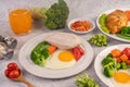 Breakfast consisting of bread, fried eggs, broccoli, carrots, tomatoes and lettuce on a white plate Royalty Free Stock Photo