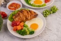 Breakfast consisting of bread, fried eggs, broccoli, carrots, tomatoes and lettuce on a white plate Royalty Free Stock Photo