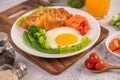 Breakfast consisting of bread, fried eggs, broccoli, carrots, tomatoes and lettuce on a white plate Royalty Free Stock Photo