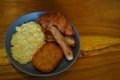 Breakfast consisting of hash browns, croissants, sausages, and scrambled eggs is served on gray ceramic plates placed on Royalty Free Stock Photo