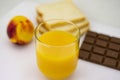 Breakfast consisting of natural orange juice, ripe peach, white bread and milk chocolate Royalty Free Stock Photo