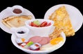 Breakfast consisting of omelet, pancakes, vegetables, sausage, c