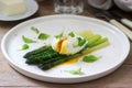 Breakfast consisting of poached egg and boiled asparagus with butter and lettuce on a wooden surface. Rustic style Royalty Free Stock Photo