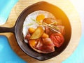 Breakfast in cooking pan with fried eggs, sausages, bacon