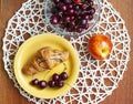 Breakfast croissant and cherries in a yellow plate, ripe peach, cherries in a glass bowl on the table