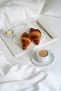 Breakfast with croissants on the napkin, knife and butter on the marble tray with a cup of coffee