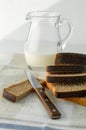 Breakfast. Dark sliced ??bread, knife and milk in a jug. Royalty Free Stock Photo