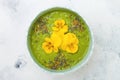 Breakfast detox green smoothie bowl topped with superfoods, chia seeds, bee pollen and edible flowers. Overhead, flat lay Royalty Free Stock Photo