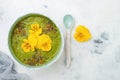 Breakfast detox green smoothie bowl topped with superfoods, chia seeds, bee pollen and edible flowers. Overhead, flat lay Royalty Free Stock Photo