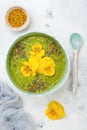 Breakfast detox green smoothie bowl topped with superfoods, chia seeds, bee pollen and edible flowers. Overhead, flat lay Royalty Free Stock Photo