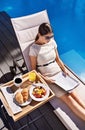Breakfast, documents and business woman poolside, reading information on work trip from above. Food, paper and woman