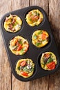 Breakfast egg muffins with bacon, tomatoes, spinach and mushrooms close-up in a baking dish. Vertical top view Royalty Free Stock Photo