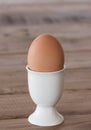 Breakfast egg in a white egg cup is on the wooden table top, vertical format Royalty Free Stock Photo